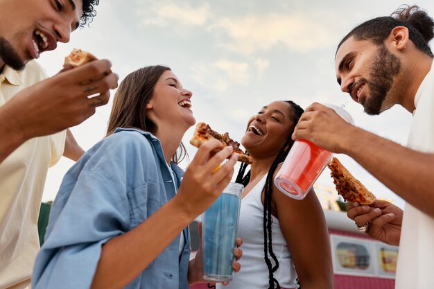 Niski kąt szczęśliwych przyjaciół z pizzą i napojami