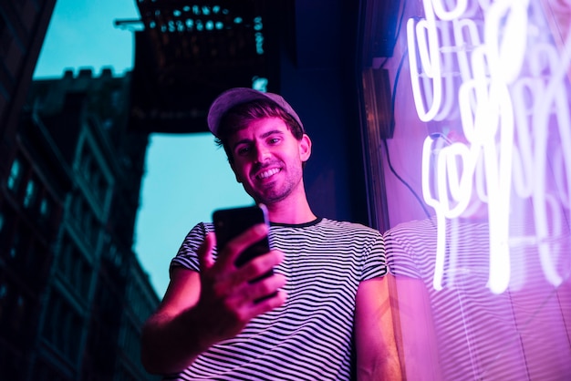 Bezpłatne zdjęcie niski widok człowieka, patrząc na jego uśmiech i telefon