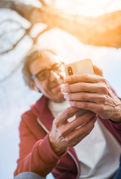 Niskiego kąta widok starszy mężczyzna używa mądrze telefon