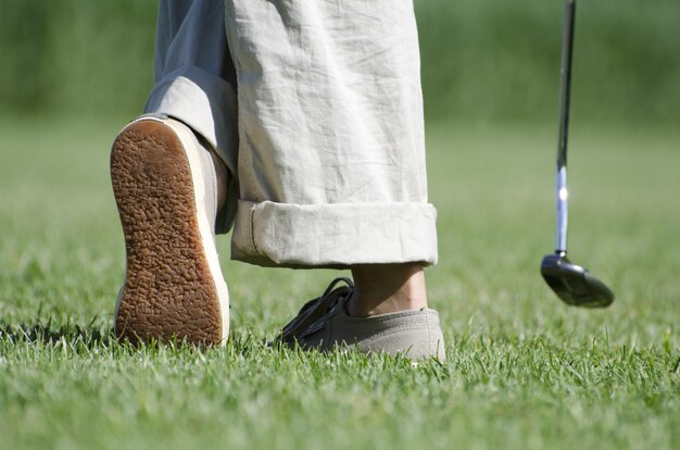 Nogi osoby grającej w golfa na zielonym krajobrazie