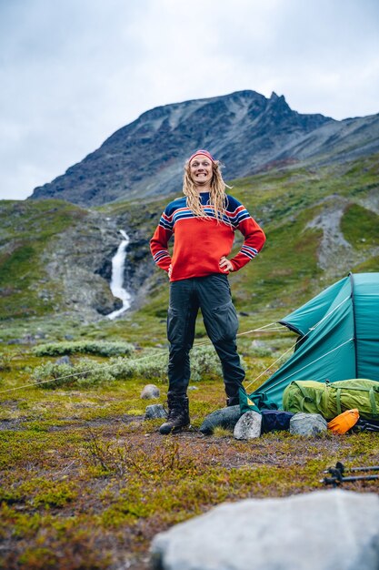 Norweg z dredami stojący przed namiotem w górach
