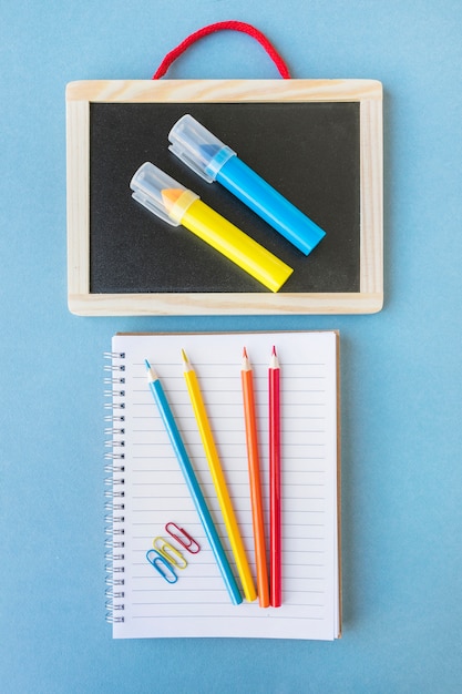 Bezpłatne zdjęcie notatnik z ołówkami zbliża blackboard z markierami