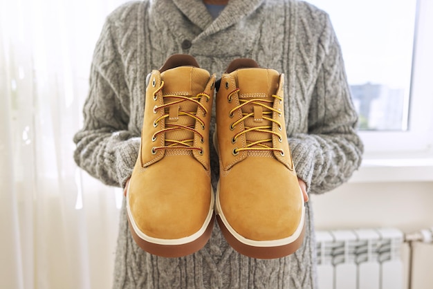 Nowe męskie skórzane brązowe wodoodporne buty trekkingowe zimowe jesienne w rękach kobiecego, modnego obuwia na zimę. rozpakowywanie butów, zakupy online z domu, sklep z modą obuwniczą