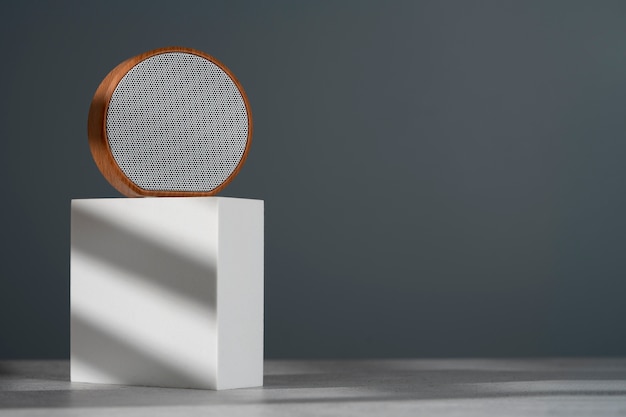 Bezpłatne zdjęcie nowoczesny okrągły głośnik bezprzewodowy o eleganckim wyglądzie zaprezentowany na geometrycznym podium