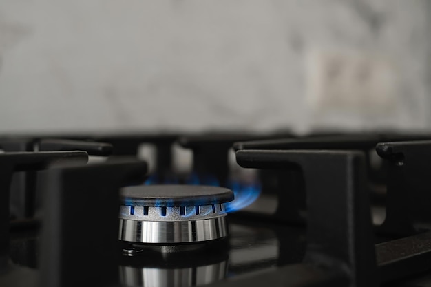 Nowoczesny piec kuchenny, gaz ziemny pali się niebieskim płomieniem. Zużycie gazu w gospodarstwie domowym. Zbliżenie, selektywne skupienie