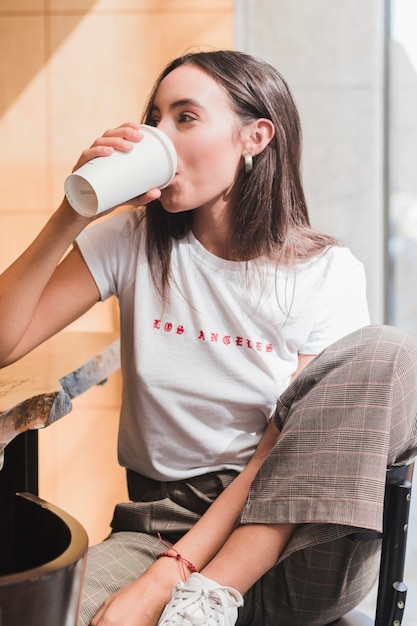 Nowożytna młoda kobieta siedzi w kawiarni pije kawę