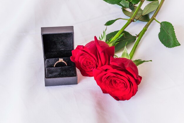 Obrączka ślubna z czerwonymi różami na bielu stole