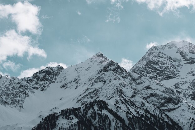 Obraz gór skalistych pokrytych śniegiem pod zachmurzonym niebem i światłem słonecznym