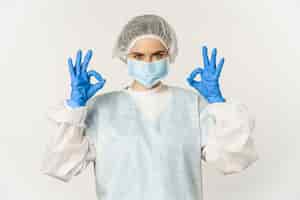 Bezpłatne zdjęcie obraz lekarza pracownika służby zdrowia w sprzęcie ochrony osobistej od covid pokazujący znak ok ok c...