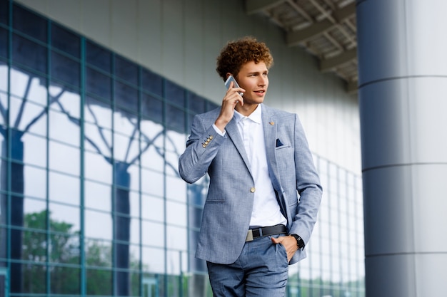 Obrazek młody redhaired biznesmen opowiada na telefonie patrzeje na boku