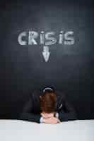 Bezpłatne zdjęcie obrazek zmęczony mężczyzna nad blackboard z kryzys inskrypcją