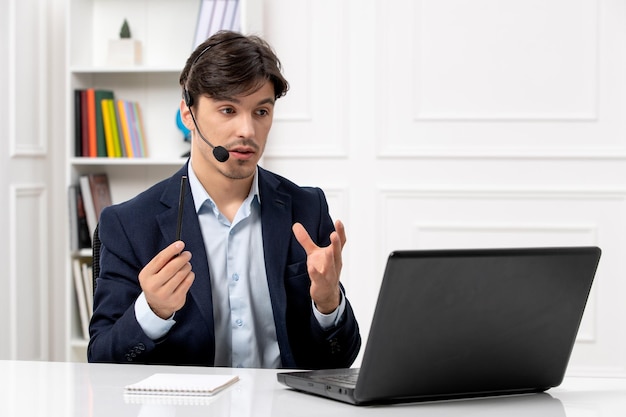 Obsługa klienta przystojny facet z zestawem słuchawkowym i laptopem w garniturze rozmawia przez wideorozmowę na komputerze