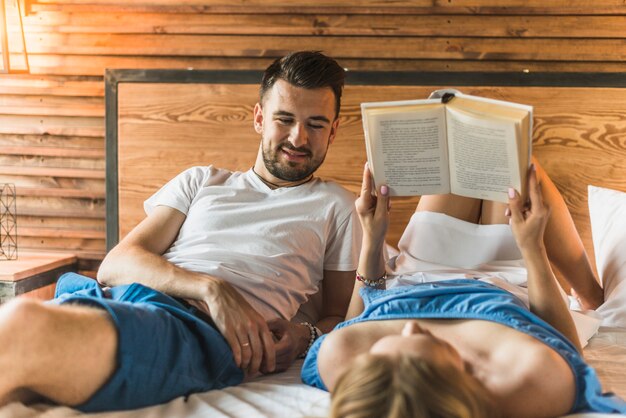 Obsługuje patrzeć jej dziewczyny relaksuje na łóżkowej czytelniczej książce