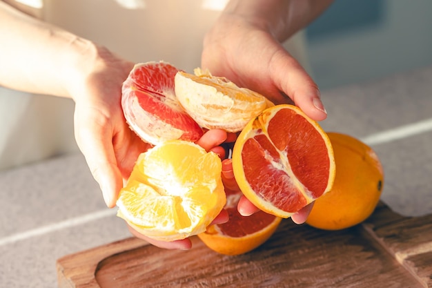 Oczerpane pomarańcze w rękach kobiet i na drewnianej desce do cięcia soku