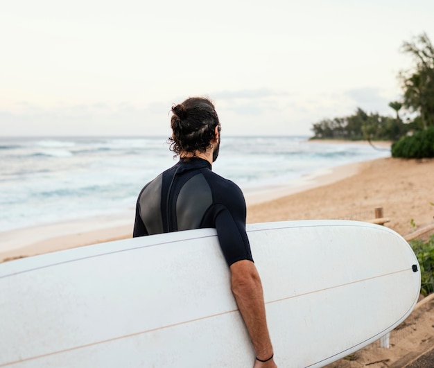 Bezpłatne zdjęcie od tyłu strzał surfer człowieka na zewnątrz