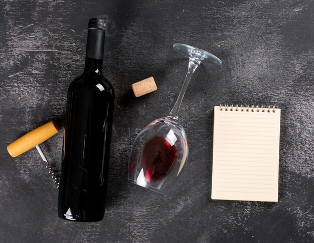 Odgórnego widoku czerwone wino z kopii przestrzenią w notatniku na czerń kamieniu horyzontalnym