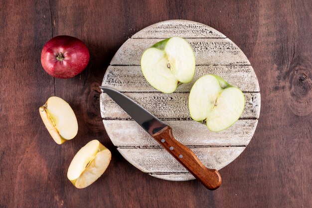 Odgórnego widoku jabłka pokrajać z nożem na białej desce na brown drewniany horyzontalnym