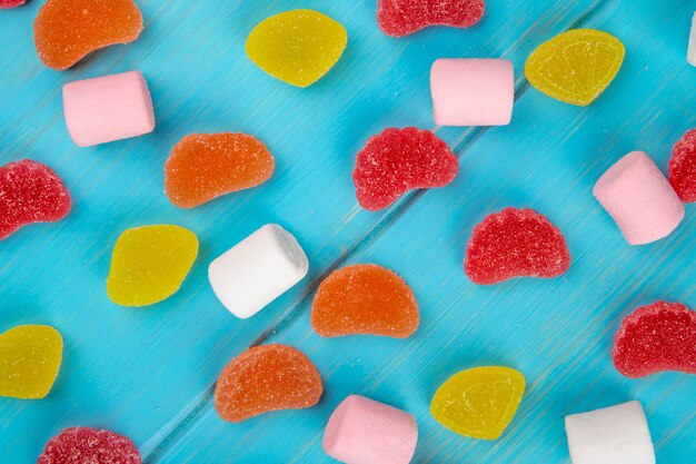 Odgórny widok kolorowi smakowici marmoladowi cukierki i marshmallows rozpraszali na błękicie