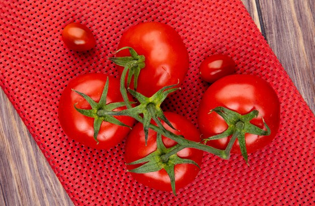 Odgórny widok pomidory na czerwonym płótnie i drewnianej powierzchni