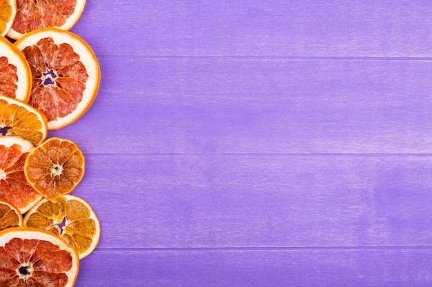 Odgórny widok rząd wysuszeni pomarańcze i grapefruitowi plasterki układał na stronie na purpurowym drewnianym tle z kopii przestrzenią