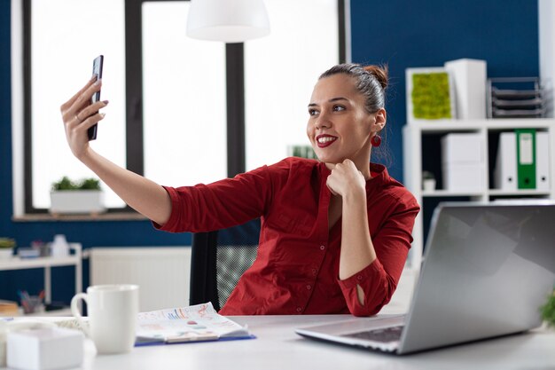 Odnosząca sukcesy bizneswoman bawi się w pracy, robiąc selfie
