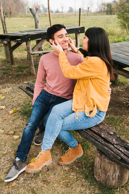 Odpoczynkowa szczęśliwa para ma zabawę w drewnianej ławce w jesień parku