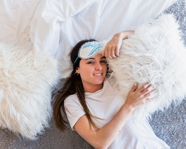 Ogólny widok kobiety leżącej na łóżku z białymi poduszkami