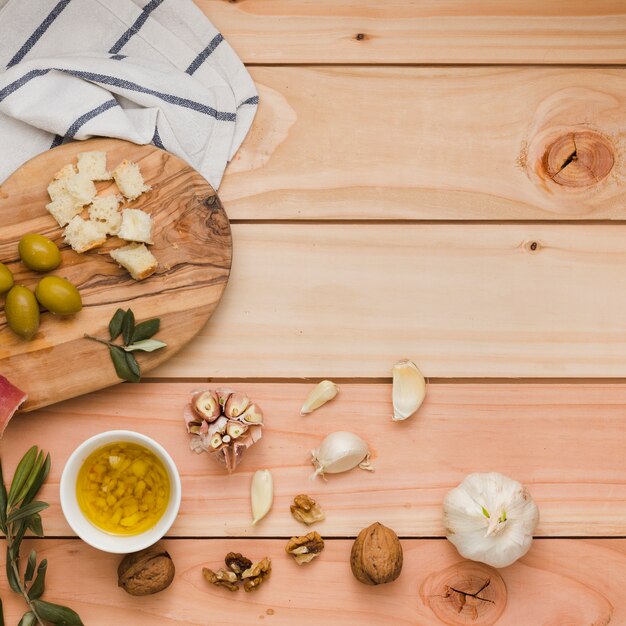 Ogólny widok oliwek; chleb; orzechy włoskie i infuzji oliwy z oliwek na drewnianym stole