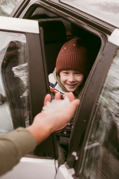 Ojciec daje synowi śnieg podczas wspólnej podróży samochodowej