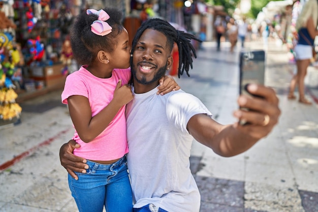 Bezpłatne zdjęcie ojciec i córka uśmiechający się pewnie robią selfie smartfonem na targu ulicznym