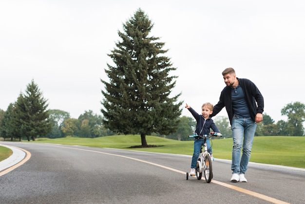 Ojciec i dziecko bawiące się w parku z rowerem