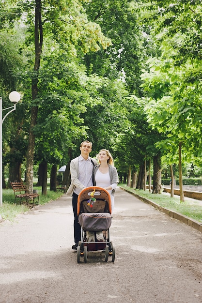 Ojciec i matka młodych chodzenia swoje dziecko przez park w wózku