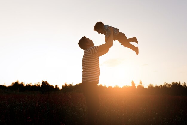 Ojciec i syn bawić się w parku przy zmierzchu czasem. Szczęśliwa rodzina ma zabawę plenerową