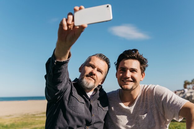 Ojciec i syn bierze selfie przy plażą