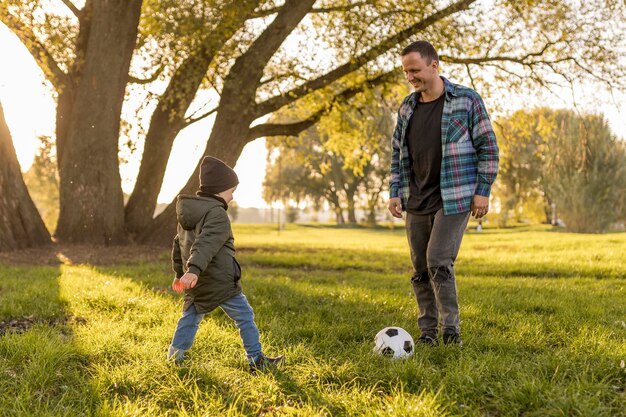 Ojciec i syn grający w piłkę nożną w parku