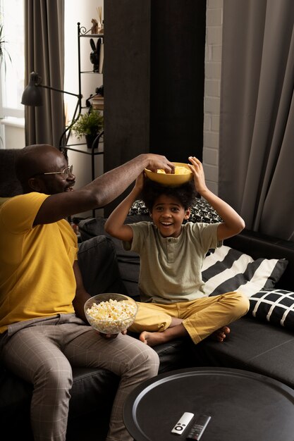 Ojciec i syn jedzą razem popcorn i chipsy ziemniaczane na kanapie