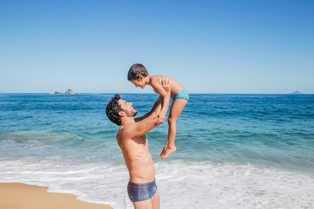 Ojciec podnoszący syna na plaży