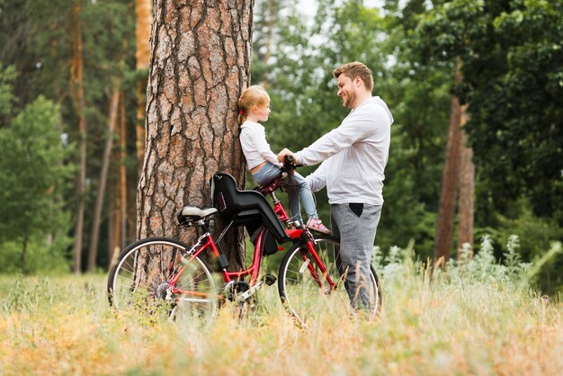 Bezpłatne zdjęcie ojciec trzyma córkę na rowerze