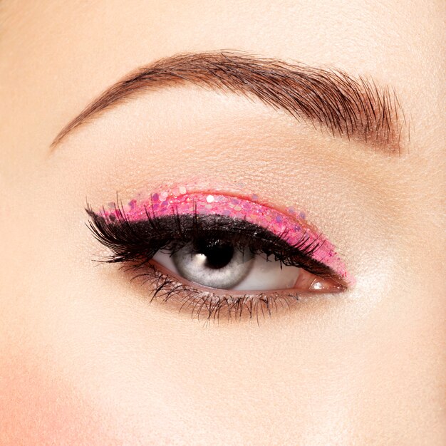 oko kobiety z różowym makijażem oczu. Obraz w stylu makro