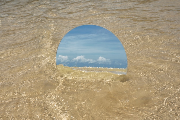 Okrągłe szklane lustro na plaży odbijające krajobraz