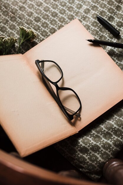 Okulary i długopisy nad otwartą książką