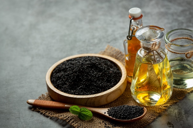 Bezpłatne zdjęcie olej sezamowy i surowe czarne nasiona sezamu na ciemnym tle