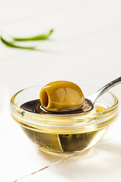 Oliwa z oliwek i gałązka oliwna na drewnianym stole