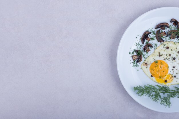 Omlet ze smażonymi grzybami na białym talerzu.