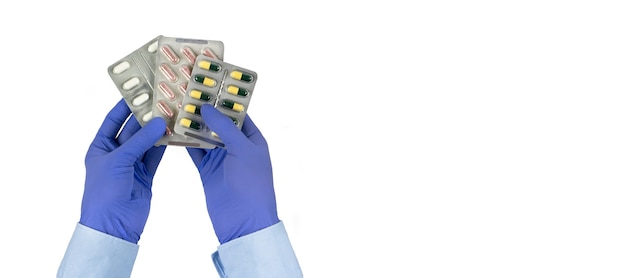 Opakowania tabletek w rękach lekarzy na białym tle męskie dłonie w niebieskich lateksowych rękawiczkach