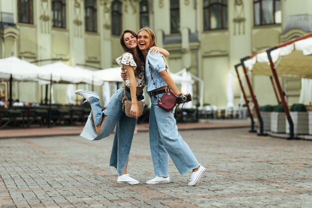 Opalona szczęśliwa brunetka i blondynka w świetnym nastroju przytulają się na zewnątrz