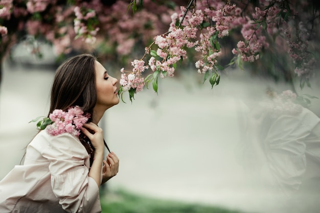 Oparta dziewczyna obwąchuje sakurę w parku