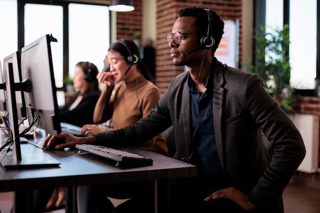 Operator odbiera telefon od klienta w dziale obsługi klienta, pomagając ludziom w obsłudze call center. Mężczyzna recepcjonista udzielający pomocy telemarketingowej na infolinię w biurze.