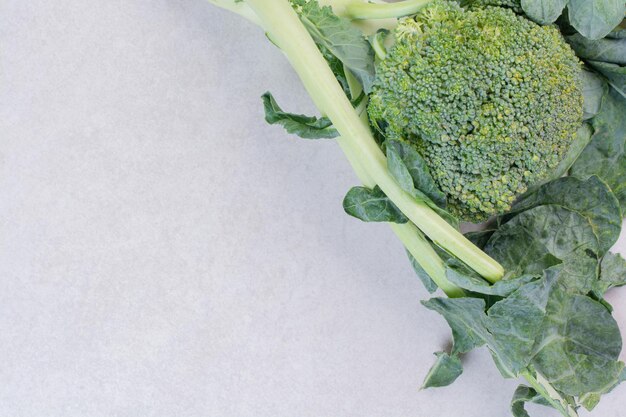 Organiczne brokuły z liśćmi na białym stole.