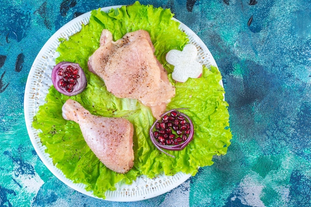 Bezpłatne zdjęcie osłonki granatu, liście sałaty z krążkiem cebuli obok mięsa z kurczaka na talerzu